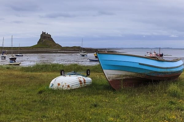 Fishing boats onshore and beach at low tide with Lindisfarne Castle and Farne Islands