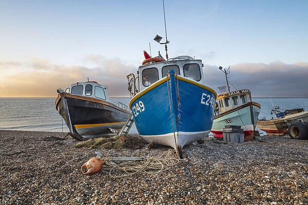 Fishing boats pulled up on shingle beach at sunrise, Beer, Jurassic Coast, Devon, England
