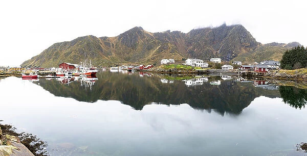 Fishing village of Ballstad and mountains mirrored in the calm waters of a fjord, Vestvagoy, Lofoten Islands, Nordland, Norway, Scandinavia, Europe