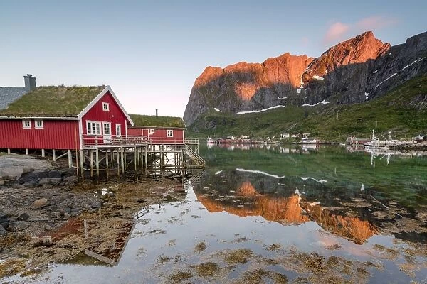 Fishing village and peaks reflected in water under midnight sun, Reine, Nordland county