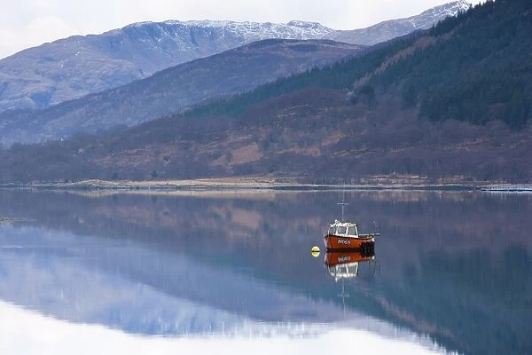 Flat calm Loch Levan with reflections of snow-capped mountains and small red fishing boat