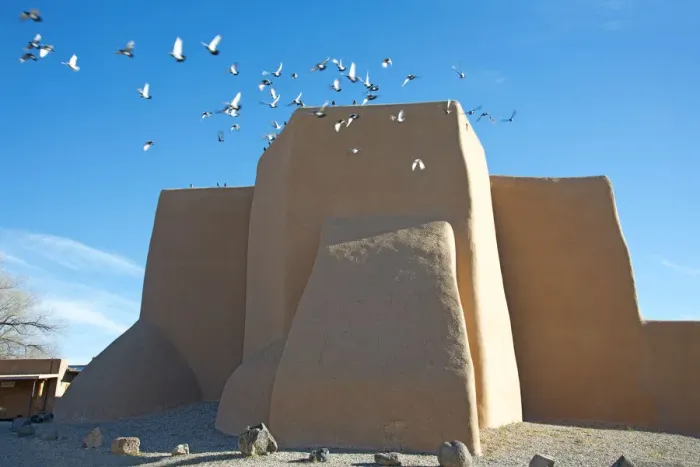 Framed Print : Flock of pigeons flying from the historic adobe San Francisco de Asis church in Taos