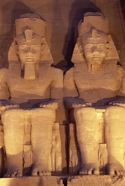 Floodlit colossi of Ramses II (Ramesses the Great), seated statues on facade of temple