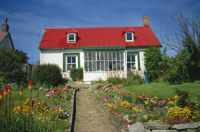 Framed Print : Flower beds line a brick path up to a typical private house, with bright red corrugated roof Framed Print : Flower beds line a brick path up to a typical private house, with bright red corrugated roof