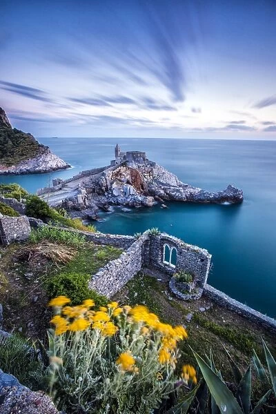 Flowers and blue sea frame the old castle and church at dusk, Portovenere, UNESCO