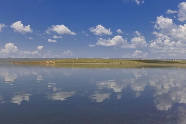 Fluffy clouds in a blue summer sky, reflected in a lake, distant reflected gers, Arkhangai