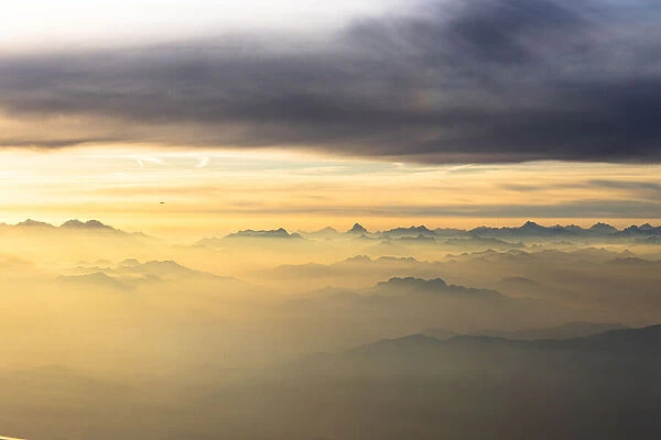 Flying over the majestic Swiss Alps in a sea of clouds at sunset, Switzerland, Europe
