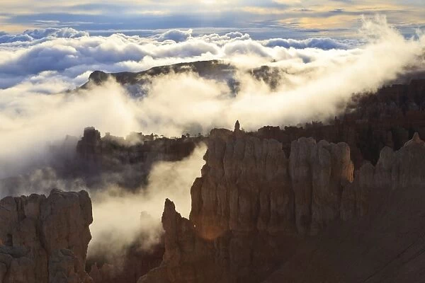 Fog and clouds of a partial temperature inversion surround the red rocks of Bryce Canyon, Bryce Canyon National Park, Utah, United States of America, North America