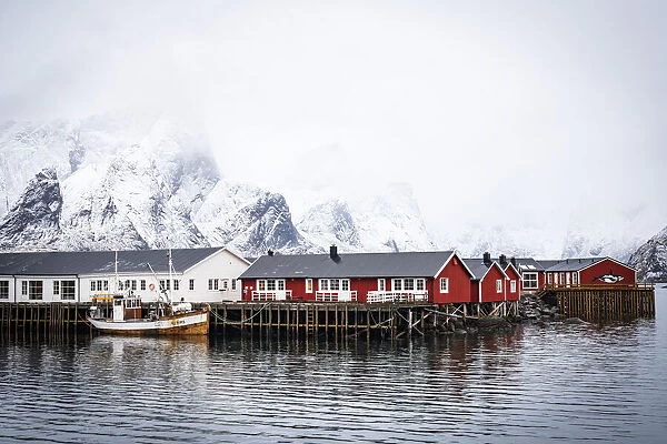 Foggy sky over snowcapped mountains and traditional Rorbu cabins by the sea, Hamnoy, Nordland county, Lofoten Islands, Norway, Scandinavia, Europe