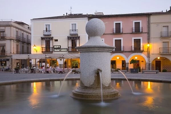 Fountain in the illuminated Plaza Mayor at dusk, Trujillo, Caceres, Extremadura