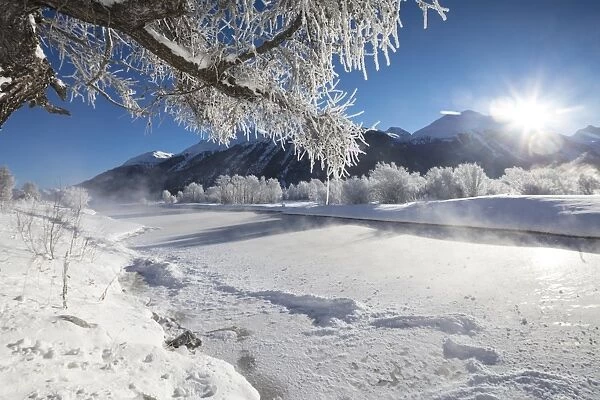 Frost on trees frame the snowy landscape and frozen river, Inn, Celerina, Maloja