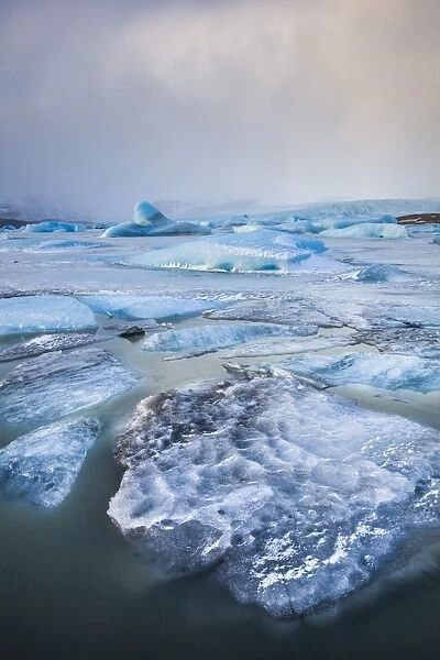 Frozen icebergs locked in the frozen waters of Fjallsarlon Glacier lagoon, South East Iceland