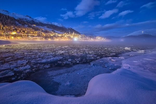 The frozen Inn river and the village of Sankt Moritz at dusk, Engadine, Canton of Grisons