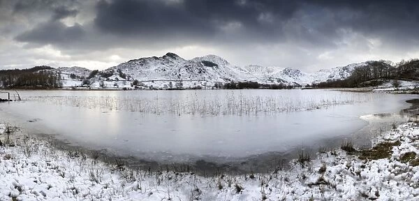 Frozen Little Langdale Tarn and snow-covered fells, near Ambleside, Lake District National Park