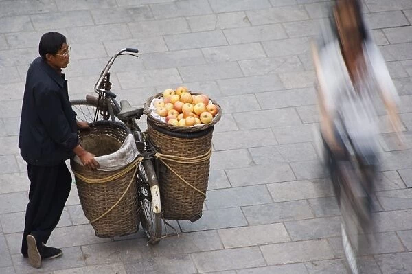 A fruit seller watching people pass by in the historic old town of Pingyao City
