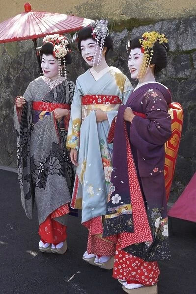 Three geishas in traditional dress posing together