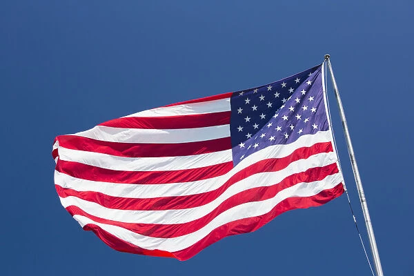 Giant US flag flying beneath a deep blue sky above Truman Avenue, Old Town, Key West