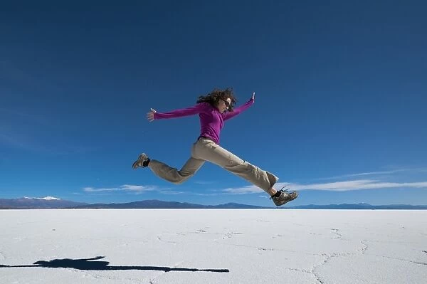 A girl leaps into the air at the Salinas Grandes (salt flats) near Purmamarca, Argentina