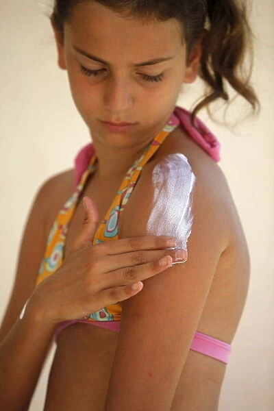 Girl putting on sunblock, Italy, Europe
