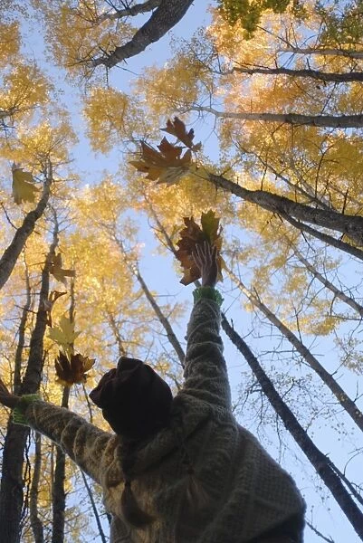Girl throws leaves in the air to celebrate autumn