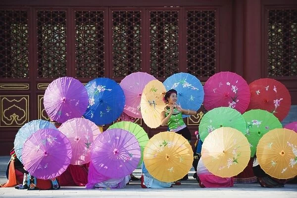 Girls dancing with colourful parasols at the Ethnic Minorities Park, Beijing, China, Asia