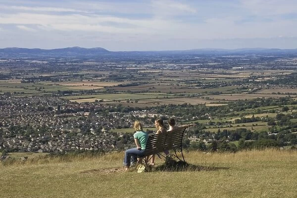 Three girls sitting on bench looking at the view over Bishops Cleeve village