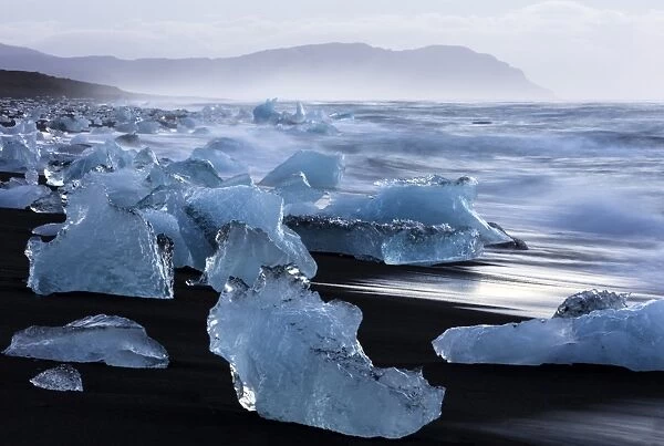 Glacial icebergs washed up from North Atlantic Ocean onto volcanic sand beach near Jokulsarlon