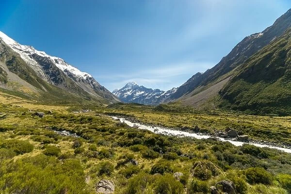 A glacier fed creek cuts through a green valley high in the mountains, South Island