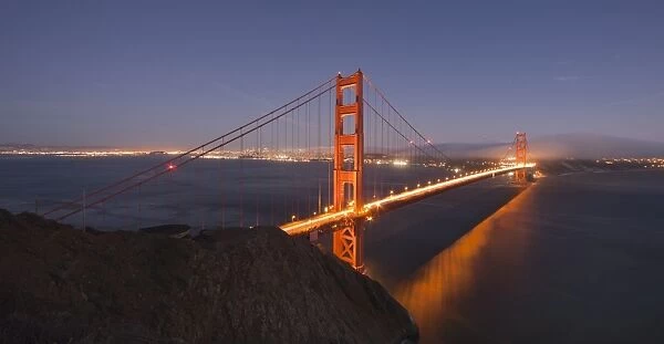 Golden Gate Bridge glowing at sunset with the San Francisco skyline behind
