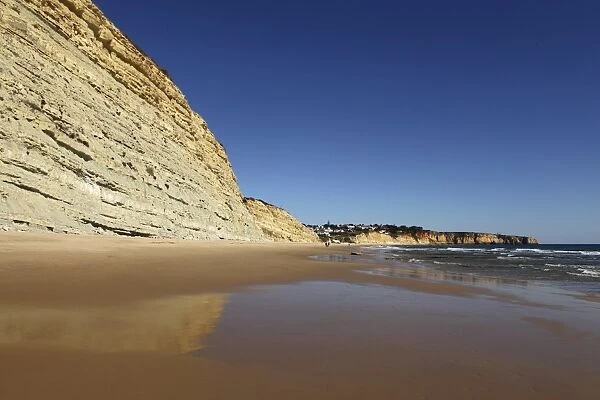 Golden sands and steep stratified cliffs, typical of the Atlantic coastline near Lagos, Algarve, Portugal, Europe