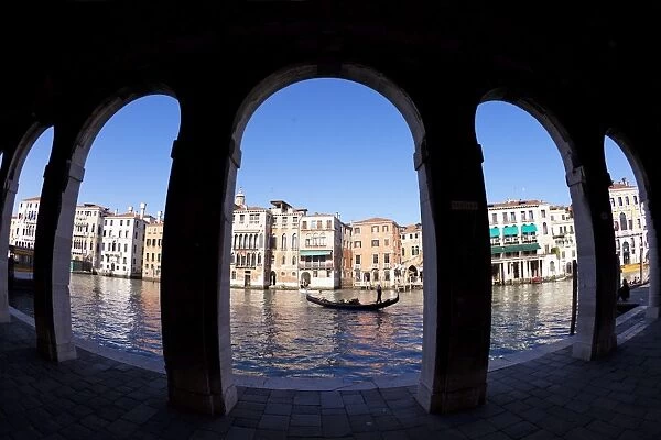 Gondola and gondolier taken through arches of the Rialto Market area, San Polo