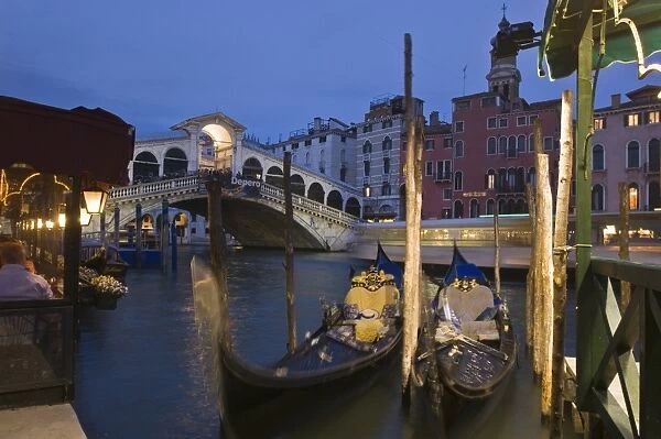 Gondolas moored on the Grand Canal at Riva del Vin, with Rialto bridge behind