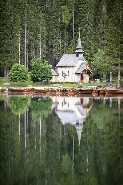 Green forest and chapel perfectly reflected in Lake Braies (Pragser Wildsee) in summer