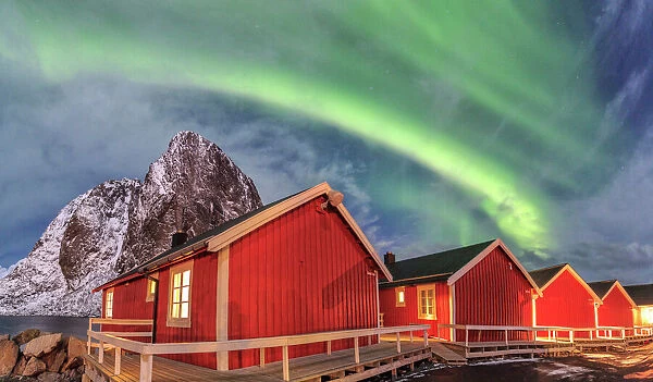 The green light of the Northern Lights (aurora borealis) lights up fishermans cabins