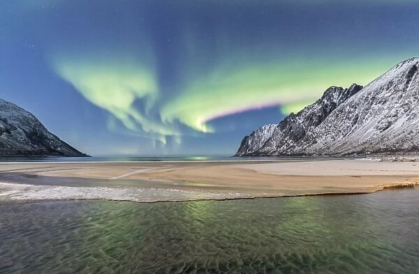 Green lights of Northern Lights (aurora borealis) reflected in the cold sea surrounded