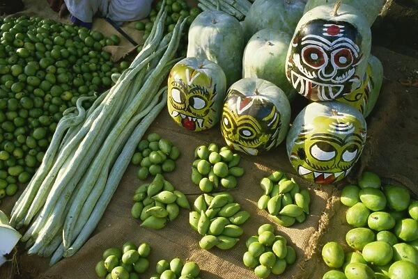 Green mangoes, snake gourds and squash painted with faces to hang in shop front to keep off evil spirits