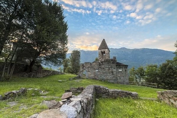 Green meadows frame the Abbey of San Pietro in Vallate at sunset, Piagno, Sondrio province