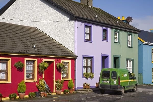 Green post van outside colourful houses in main street