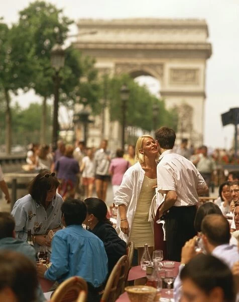 Greeting friends at an outdoor cafe on the Champs Elysees with the Arc de Triomphe behind
