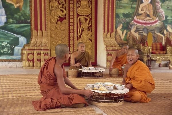 A group of Buddhist monks in saffron robes sitting on the floor