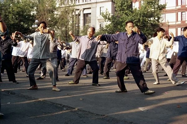 A group of men and women doing tai-chi exercises in the open air on the Bund in Shanghai