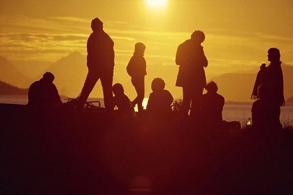 Group of people silhouetted against midnight sun