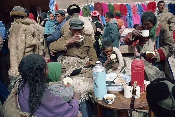 A group of Tibetans eating at the bazaar at T'Aer Monastery, Qinghai province