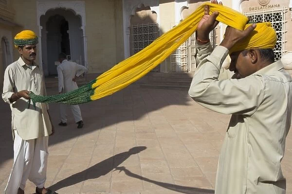 Guard winding his yellow and green turban