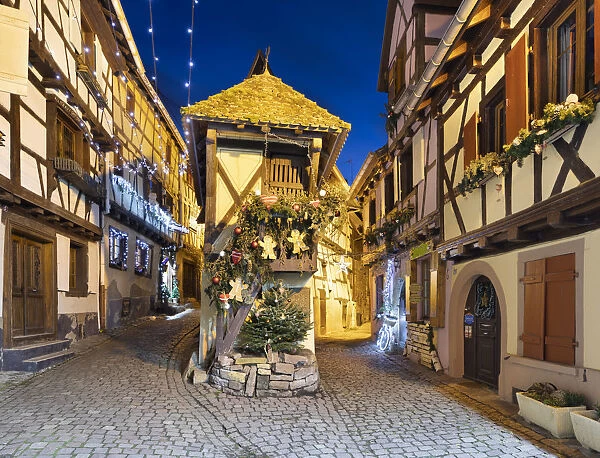 Half-timbered houses along Rue du Rempart Sud lit up with Christmas decorations at night