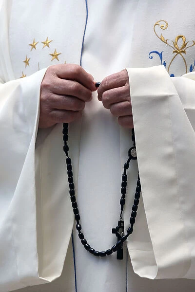 Hand-carved Roman Catholic rosary beads, priest praying The Mystery of the Holy Rosary
