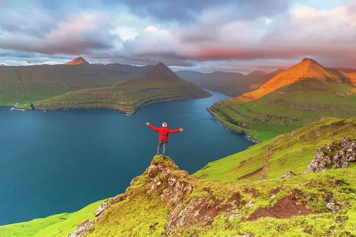 Framed Print : Happy hiker stands on top of the cliff overlooking the fjord of Funningur, Eysturoy island, Faroe islands, Denmark, Europe Framed Print : Happy hiker stands on top of the cliff overlooking the fjord of Funningur, Eysturoy island, Faroe islands, Denmark, Europe