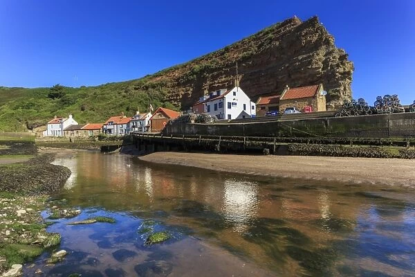 Harbour cottages beneath steep cliffs, fishing village, low tide in summer, Staithes