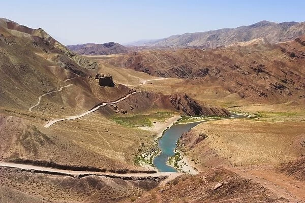 Hari Rud river flowing through fertile valley at base of red rock mountains