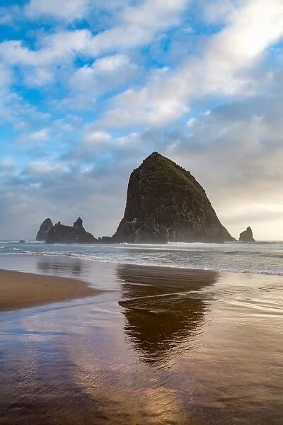 Haystack Rock reflected on the shoreline at Cannon Beach on the Pacific Northwest coast